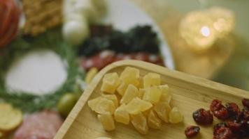 assiette de charcuterie avec salami, différentes sortes de fromages. il contient des fruits secs, diverses noix et du miel. arrangement de vacances avec des bougies allumées video