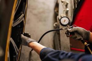 Mechanic checks tire pressure in yellow sport car suv. photo