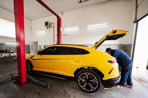 Mechanic open trunk of yellow sport car suv. photo