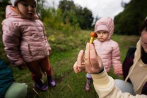 Mother and children searching mushrooms in the wild forest. Woman hold buttercup mushroom. photo