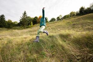 niño divirtiéndose correr y saltar al aire libre cerca del bosque. foto