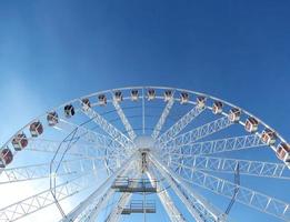 The top part of the giant ferris wheel in Krakow against a bright blue sky in the midday light. Horizontal photo with place for text.