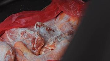 Close-up view of hands in gloves packing chicken legs from a box into individual plastic bags. Process of freezing meat for further use at home. 4k video with light play