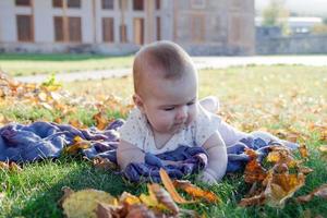 una niña linda está jugando con hojas amarillas secas en un parque por primera vez en su vida. foto