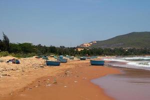 View on a sandy beach near to sea and fishing village with a lot of garbage. Pollution of a coastline. Mui Ne, Vietnam. photo