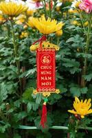 Vietnamese and Chinese New Year decoration on a background of yellow flowers. The inscription is translated - Happy New Year. Hue, Vietnam. photo