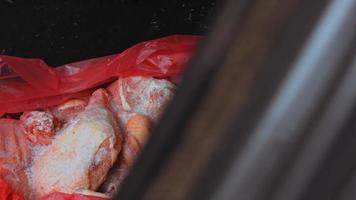 Close-up view of hands in gloves packing chicken legs from a box into individual plastic bags. Process of freezing meat for further use at home. 4k video with light play