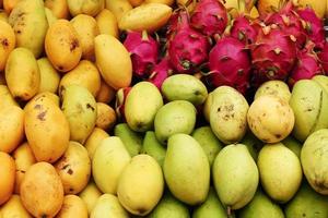 Exotic tropical fruits - mango, dragon fruit - closeup on a market, top view. photo