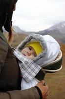 Portrait of little girl in ergo carrier with her mother on a background of autumn mountains. photo