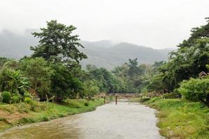 Rural landscape with a bamboo bridge over the small river on a background of mountains and forest. Pai, Mae Hong Soon Province, Thailand. photo