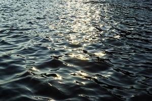 reflejo del sol en el agua durante una puesta de sol. foto