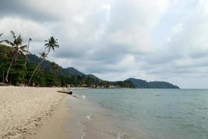 paisaje tropical con mar azul, playa de arena, palmeras y cielo nublado en un clima tormentoso. ko chang, tailandia. foto