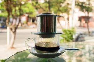 Drip Black Coffee in Vietnamese style with condensed milk on a glass table. Traditional method of making coffee. photo