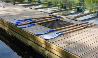 Classic wooden boat oars. Plastic boat paddles lie on a wooden pier, boat rental in the park photo