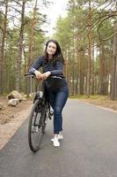 una mujer en bicicleta, una chica europea se detuvo en una bicicleta para relajarse en el bosque foto