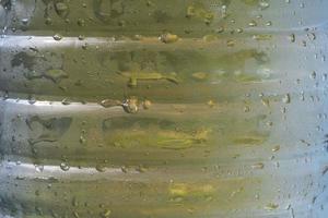 drops of condensate drain from a cold bottle of drinking water on a hot day, abstract background with water and drops photo