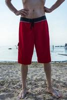 a thin tall man in red bathing shorts on the beach on a hot sunny day photo