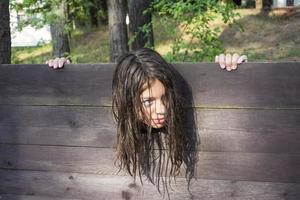 la cabeza de una niña con el pelo largo y despeinado sujeta en una guillotina, una escena de una ejecución medieval, una oración foto