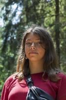 retrato de una linda adolescente europea en el bosque en verano en un día soleado, una chica con un vestido burdeos foto