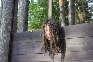 la cabeza de una niña con el pelo largo y despeinado sujeta en una guillotina, una escena de una ejecución medieval, una oración foto