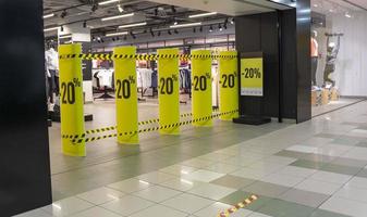 la entrada principal a la tienda de ropa deportiva de moda en el centro comercial y de entretenimiento está restringida debido a la pandemia del coronovirus, descuentos, venta foto