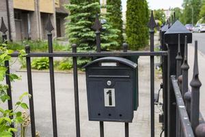 mailbox of a private house, a black metal mailbox installed on the fence grid of a house photo