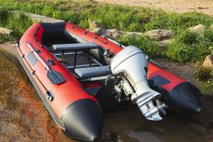 Red inflatable rubber boat with a motor near the lake shore, fishing, tourism, active recreation photo