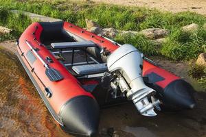 bote de goma inflable rojo con motor cerca de la orilla del lago, pesca, turismo, recreación activa foto