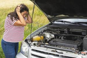 A broken car. A young woman stands on the road by a broken car in the middle of nowhere. photo