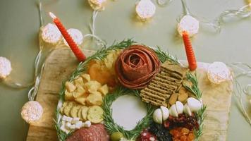 Charcuterie plate with salami, different kinds of cheese. It has dried fruits, various nuts and honey. Holiday arrangement with burning candles video