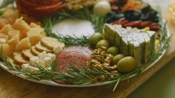 Charcuterie plate with salami, different kinds of cheese. It has dried fruits, various nuts and honey. Holiday arrangement with burning candles