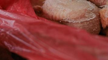 Close-up view of hands in gloves packing chicken legs from a box into individual plastic bags. Process of freezing meat for further use at home. 4k video with light play