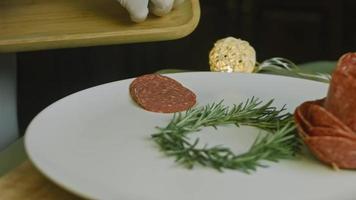 prato de charcutaria com salame, diferentes tipos de queijo. tem frutas secas, nozes diversas e mel. arranjo de férias com velas acesas video