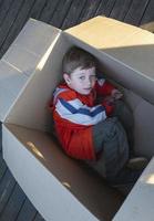 cute european boy lying in a cardboard box, homeless life, package photo