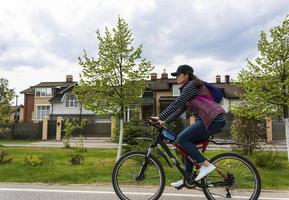 attractive young woman with big thighs rides a bicycle through the city streets photo