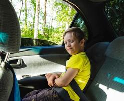 happy European boy rides in the car in the back seat, the child is smiling, he is wearing a seat belt photo