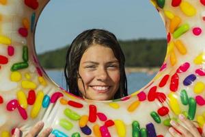 Cute teen girl with colorful inflatable swimming circle swims in the blue water of the sea on a hot sunny day photo