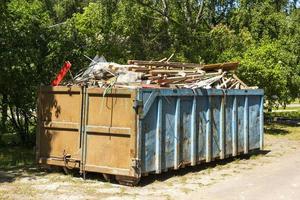 garbage container equipped for transportation by truck, filled with construction debris large iron container, construction waste photo