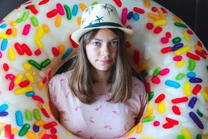 retrato de una adolescente europea con un donut inflable para nadar en un sombrero foto