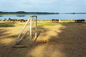 gol de fútbol y pelota en la playa. sol, agua y arena. la playa en el lago de la base turística. foto