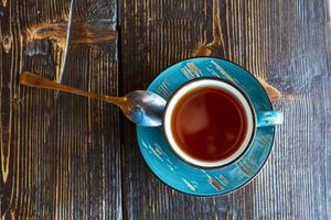 A cup of tea, a saucer and a teaspoon on a rough wooden table in a cafe, brunch. Fresh tea, calm. Top view photo