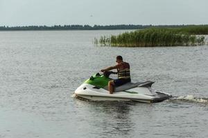 A young guy rides a jet ski on the lake, a man rides a jet ski, active lifestyle, summer, water, heat, vacation photo