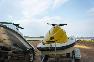 A jet ski parked on the beach against the background of the lake and the blue sky. For the design of an active lifestyle photo