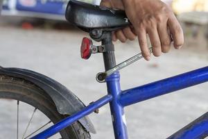 la mano del mecánico sostiene las llaves de anillo para aflojar la tuerca oxidada en la reparación de bicicletas. foto