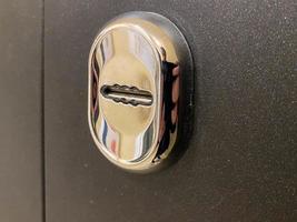 nuevo ojo de cerradura cromado de metal brillante para una llave en una puerta de entrada de metal negro en el pasillo de entrada a la entrada del apartamento foto