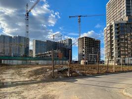 Construction of a new district of a quarter of a modern city with new construction of houses and buildings with the help of large industrial cranes for repairs photo