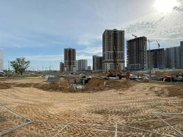 los edificios y las casas altos, modernos y hermosos son rascacielos de hormigón construidos industrialmente utilizando tecnología de marco monolítico con la ayuda de equipos de construcción y grúas foto