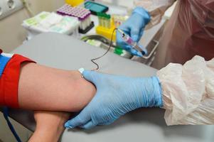 sacar sangre de una vena. sujetando la vena con un torniquete médico desechable. punción de la vena con una aguja desechable estéril. la sangre entra en un tubo de ensayo para la investigación en el laboratorio foto