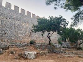 Large stone wall of an old ancient medieval fortress made of cobblestones against a blue sky photo