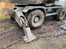 a tractor with large, black wheels in the mud. large construction equipment for the construction of houses. black wheel stuck in a puddle photo